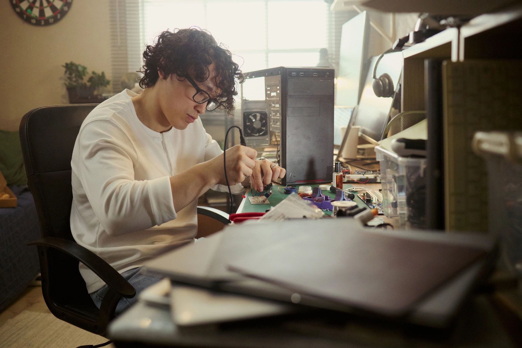 Technician performing detailed electronics repair work at a service bench